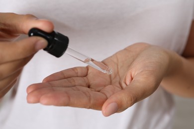 Woman applying cosmetic serum onto her hand, closeup