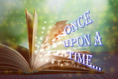 Image of Open book of fairy tales with magic light and text Once upon a time 
