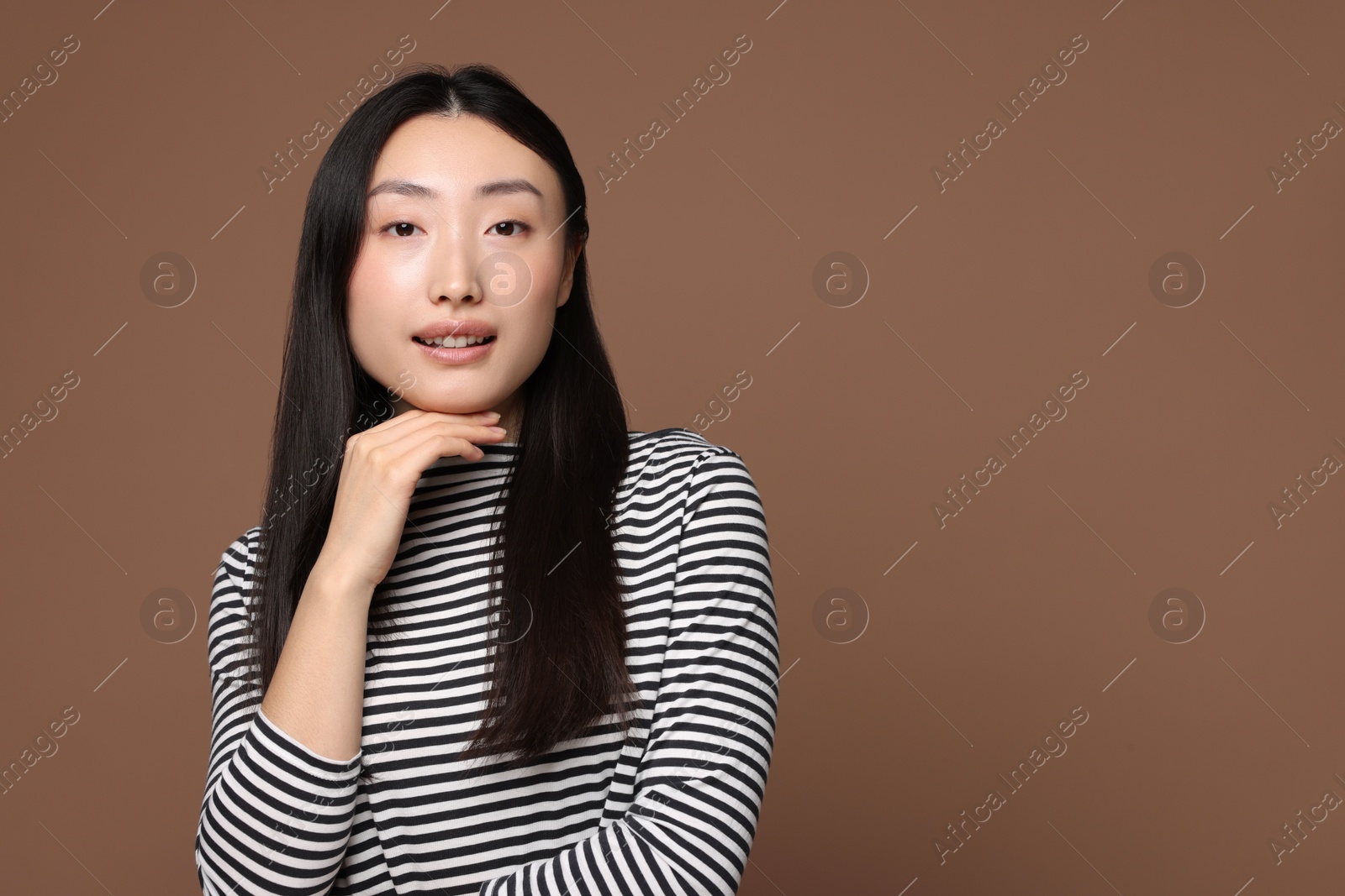 Photo of Portrait of smiling woman on brown background. Space for text