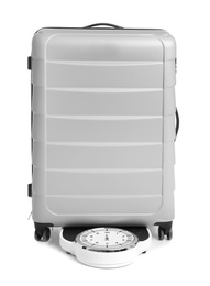 Weighing stylish suitcase on scales, white background