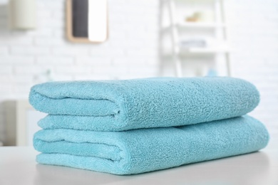 Stack of fresh towels on table in bathroom, closeup. Space for text