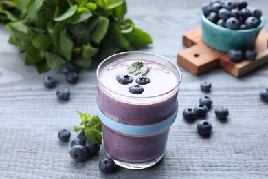 Glass of freshly made blueberry smoothie on grey wooden table
