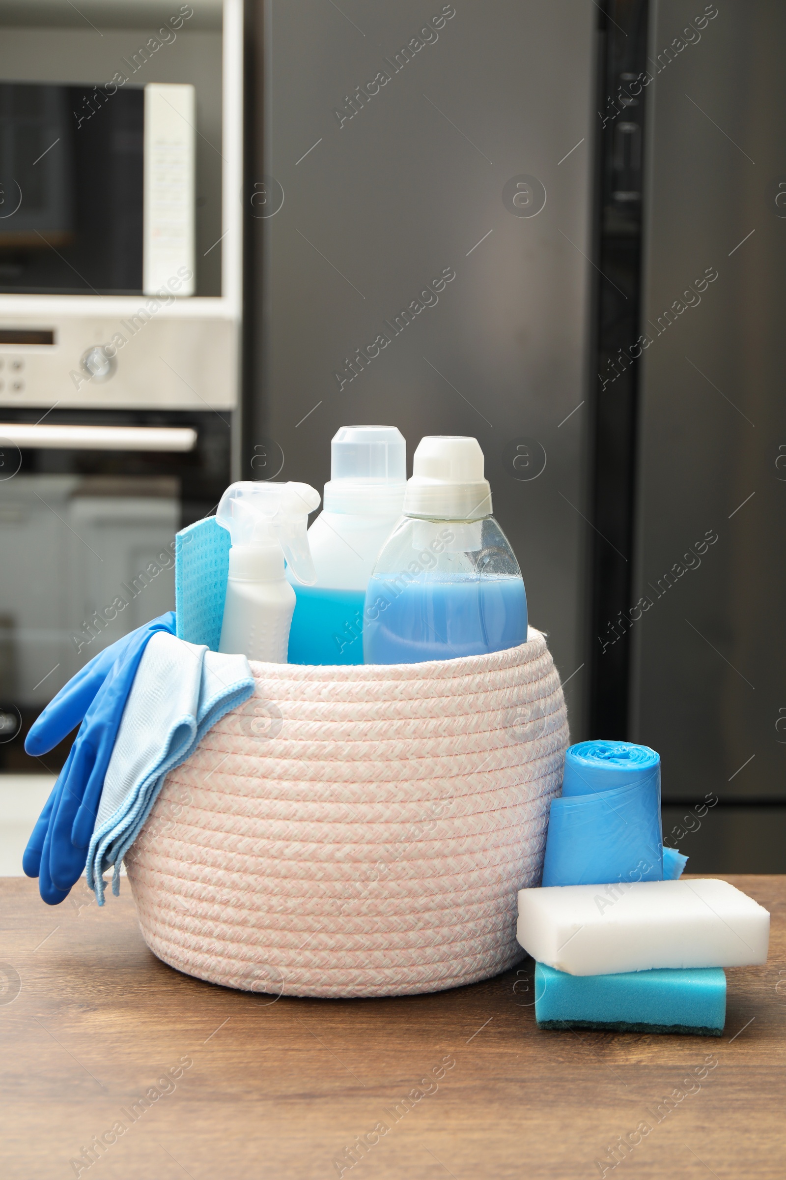 Photo of Different cleaning supplies in basket on table