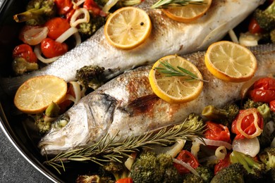 Photo of Baked fish with vegetables, rosemary and lemon on black textured table, top view