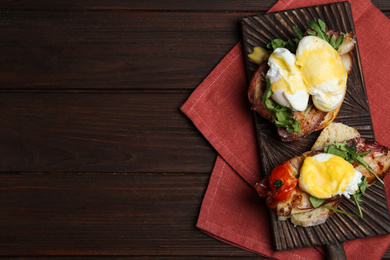 Delicious eggs Benedict served on wooden table, flat lay. Space for text