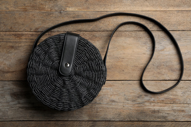 Photo of Stylish small woman's bag on wooden background, top view