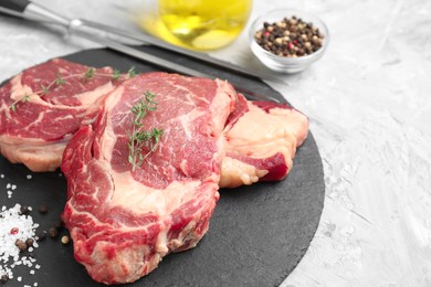 Photo of Fresh raw beef cut with different spices on light grey textured table, closeup. Space for text