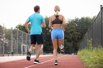 Photo of Healthy lifestyle. Sporty couple running at stadium, back view