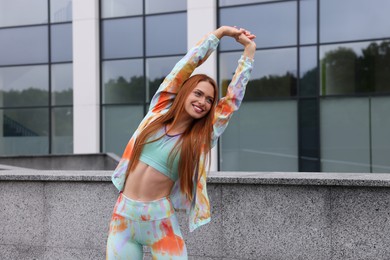 Beautiful woman in gym clothes doing exercises on street