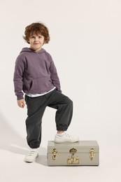 Photo of Fashion concept. Stylish boy with vintage suitcase on white background