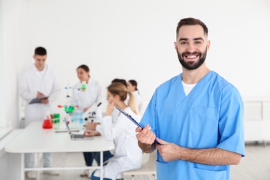 Photo of Portrait of medical student with clipboard in scientific laboratory. Space for text