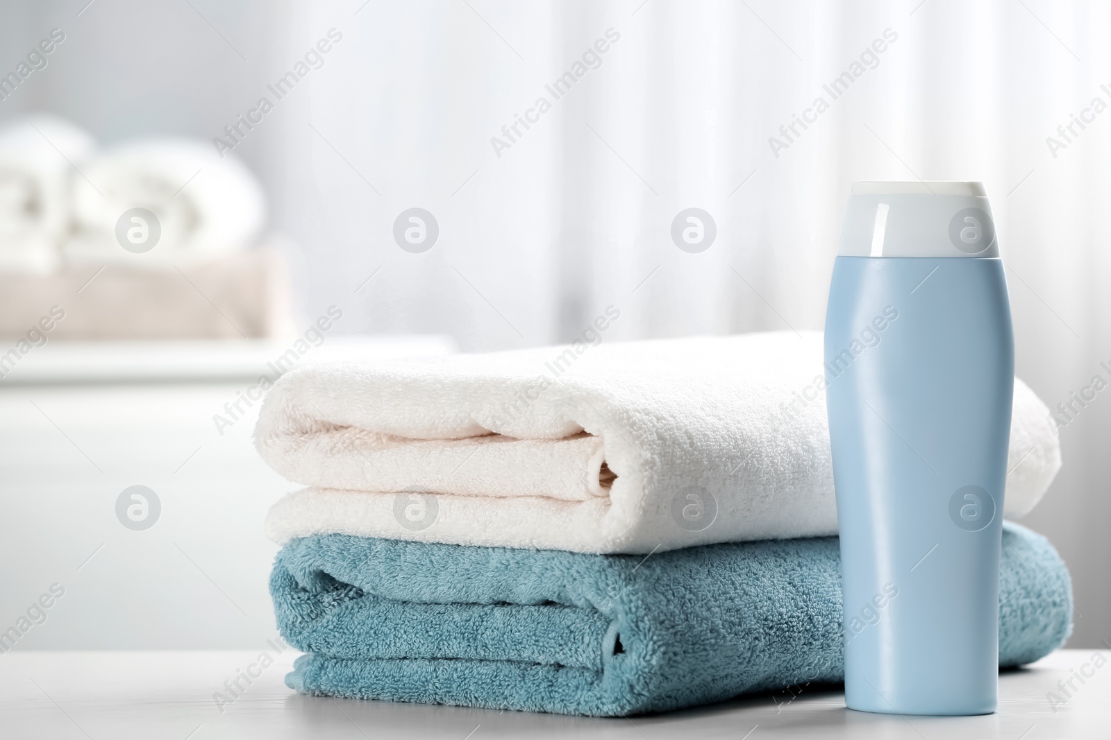 Photo of Clean towels and shampoo bottle on table. Space for text