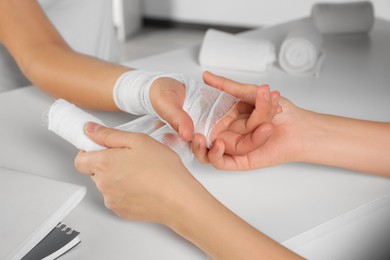 Doctor applying bandage onto patient's hand in hospital, closeup