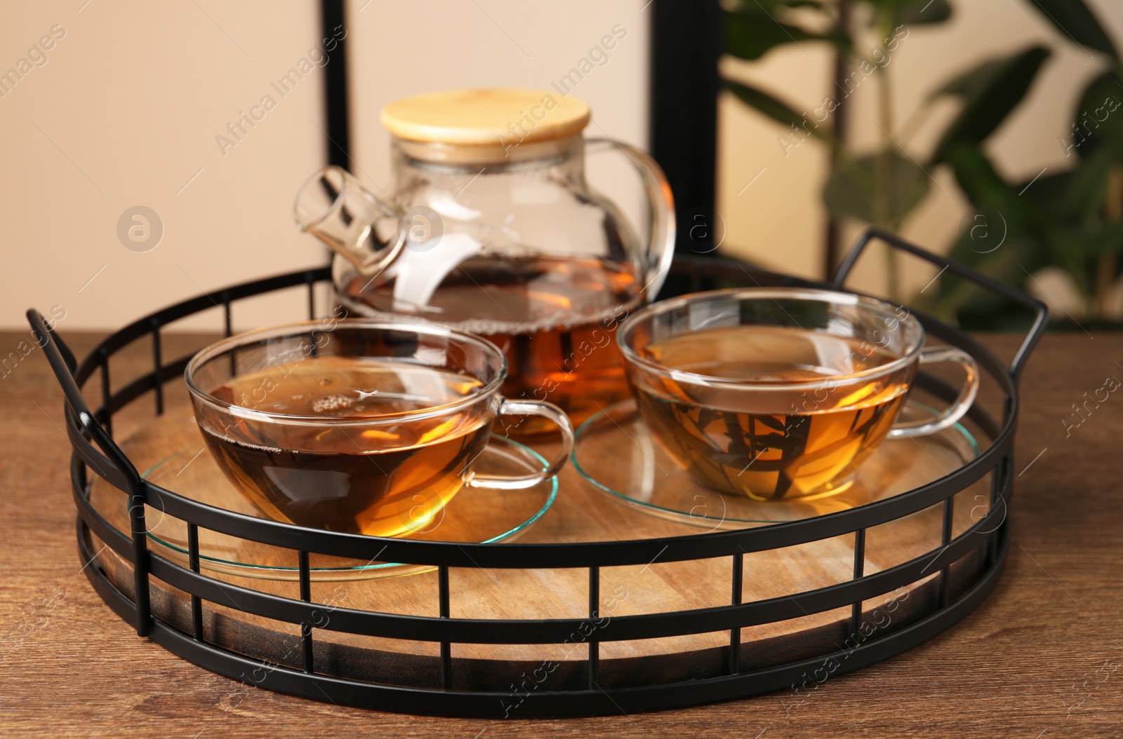 Photo of Aromatic tea in glass cups and teapot on wooden table, closeup