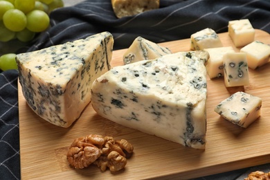 Photo of Board of delicious blue cheese with snacks on table