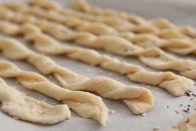 Photo of Homemade breadsticks with sesame on baking sheet, closeup. Cooking traditional grissini