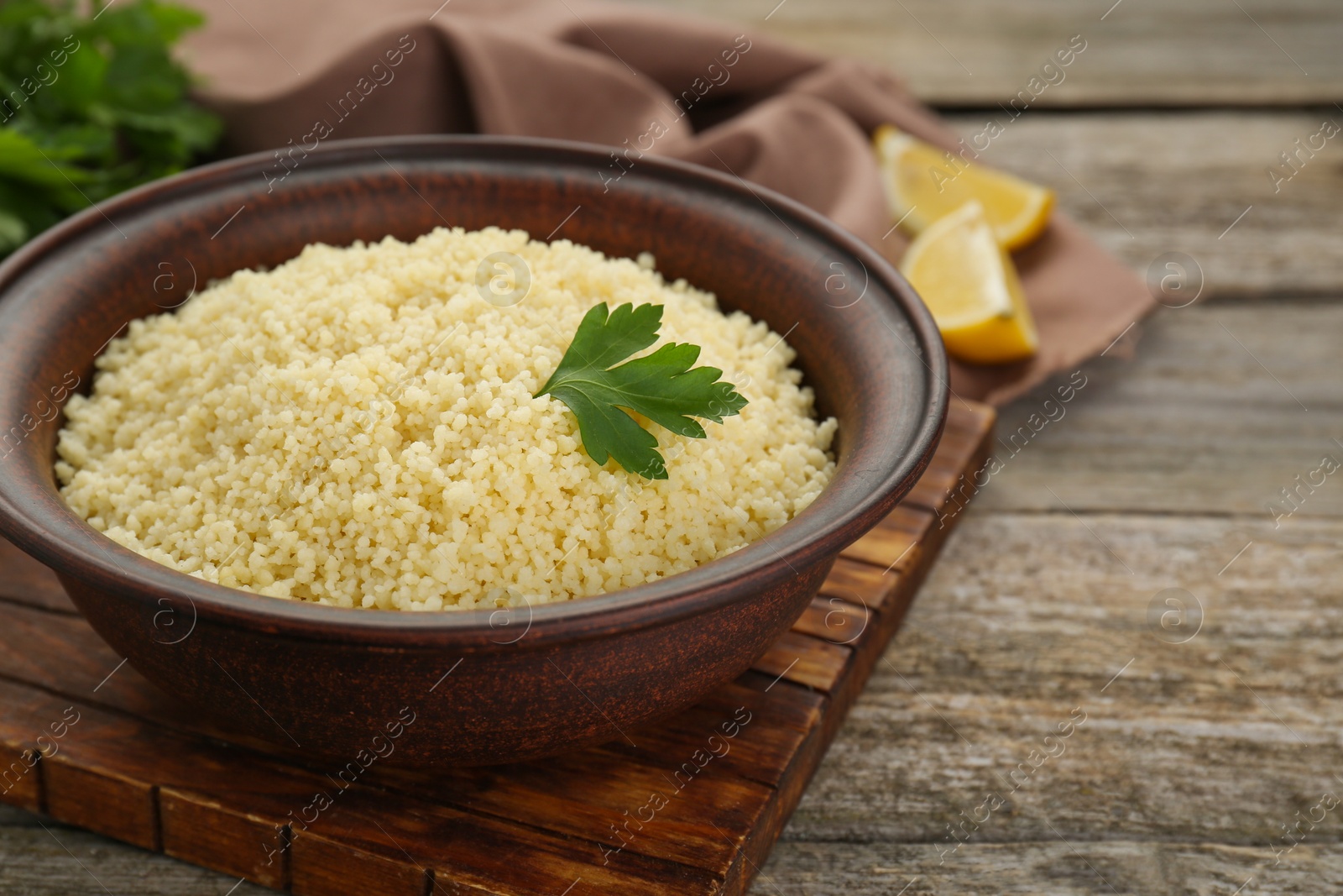 Photo of Tasty couscous with parsley on wooden table, closeup