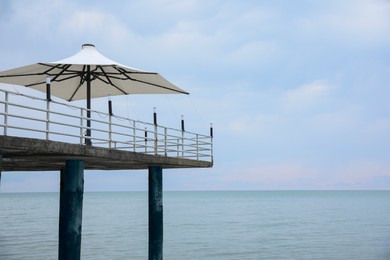 Photo of Beautiful view of pier with beach umbrellas near sea. Space for text