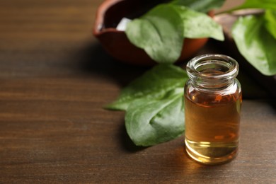 Photo of Bottle of broadleaf plantain extract and leaves on wooden table, space for text