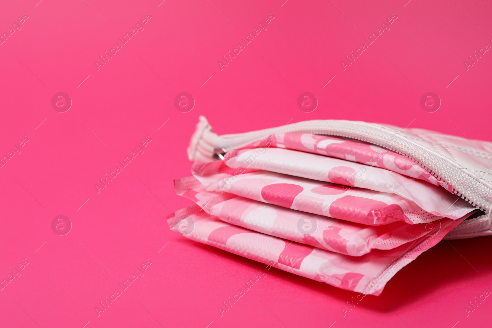 Photo of White bag with menstrual pads on pink background, closeup. Space for text