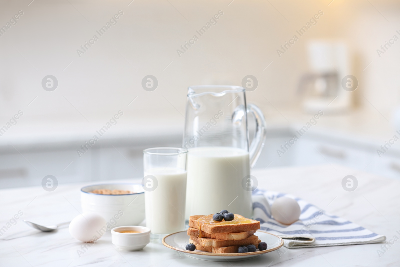 Photo of Toasted bread with jam and blueberries on white marble table in kitchen