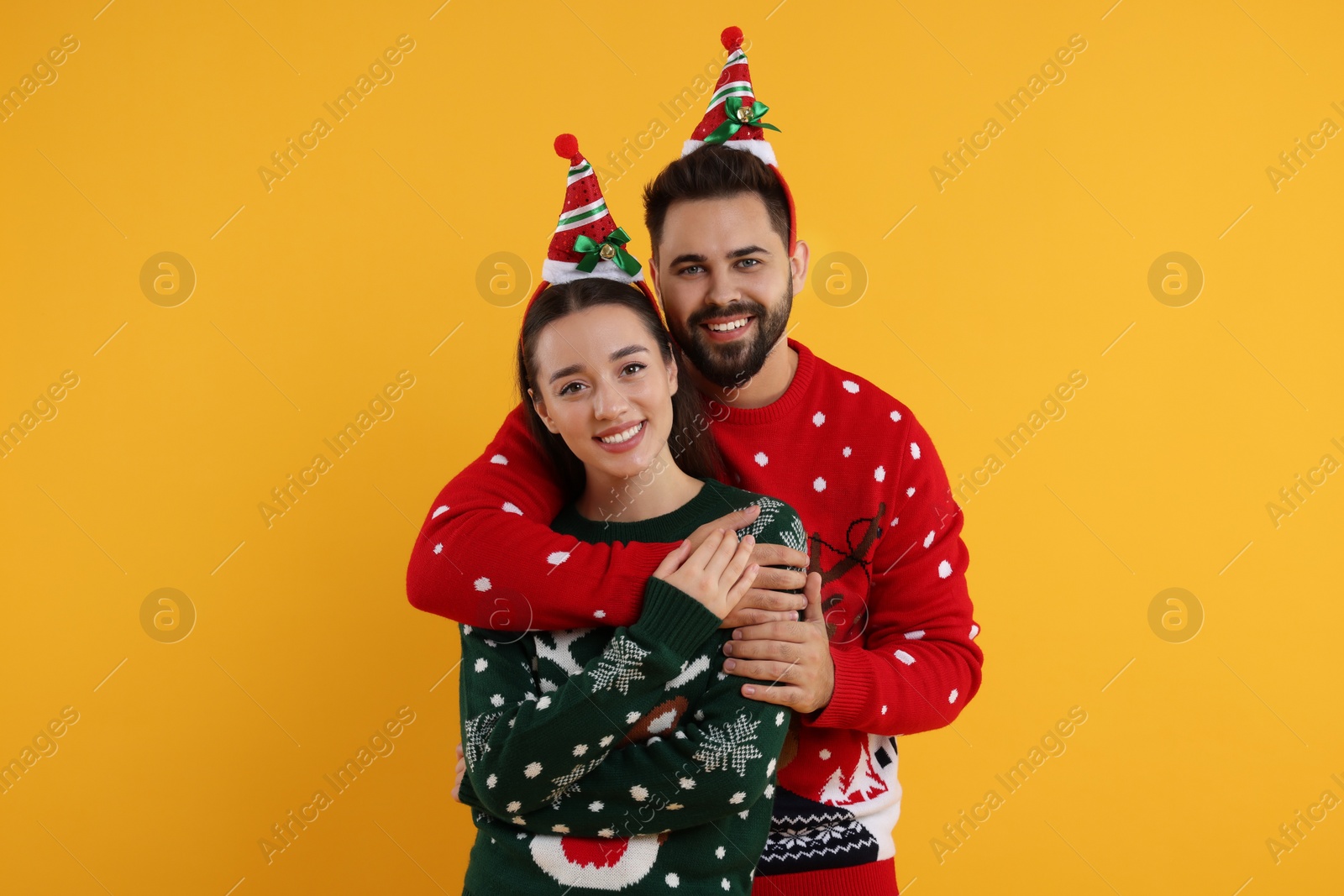 Photo of Happy young couple in Christmas sweaters on orange background