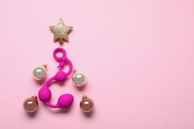 Photo of Christmas tree made with decorative balls, star and sex toy on pink background, flat lay. Space for text