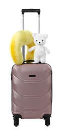 Soft travel pillow and toy bear on suitcase isolated on white