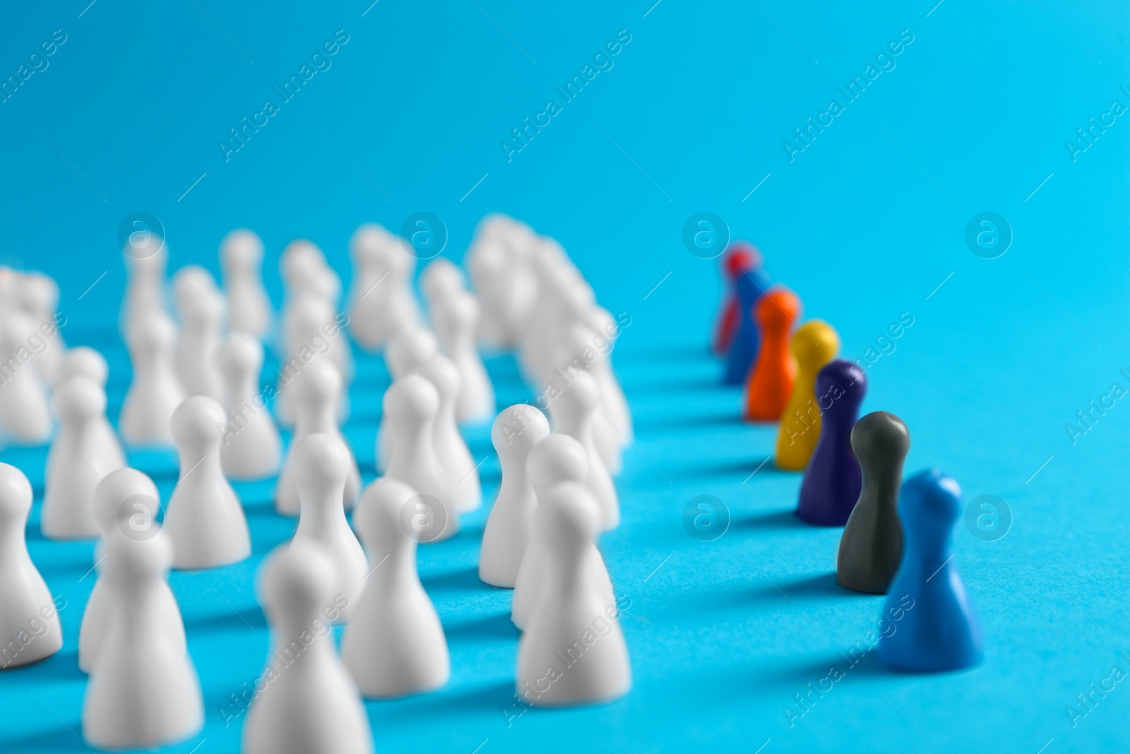 Photo of Colorful pawns on light blue background. Social inclusion concept