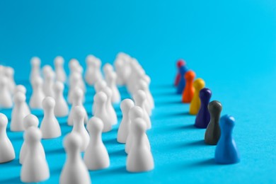 Photo of Colorful pawns on light blue background. Social inclusion concept