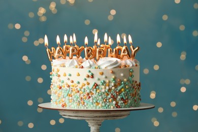 Photo of Beautiful birthday cake with burning candles on stand against festive lights