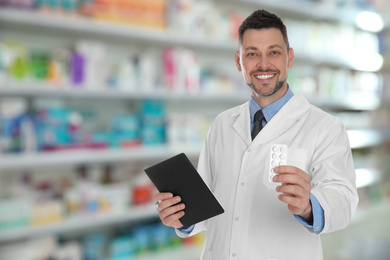 Image of Professional pharmacist with pills and clipboard in modern drugstore