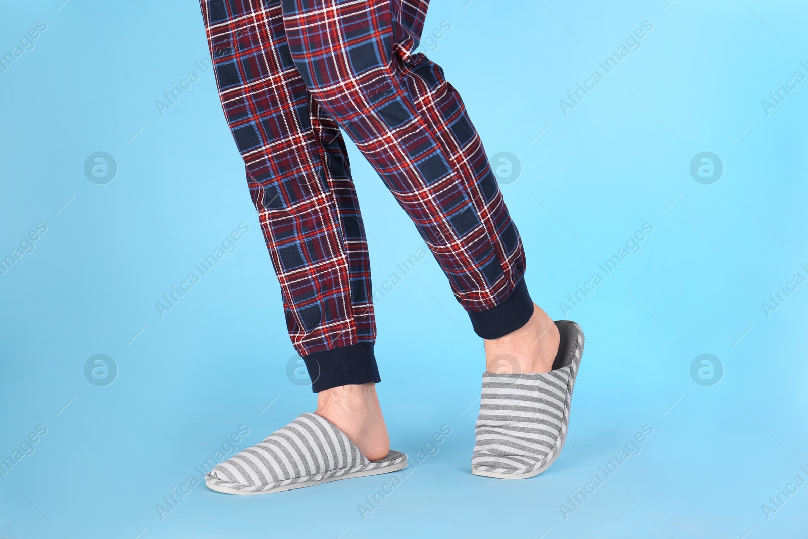 Photo of Man in warm soft slippers on light blue background, closeup