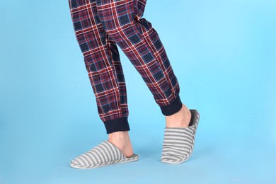 Photo of Man in warm soft slippers on light blue background, closeup