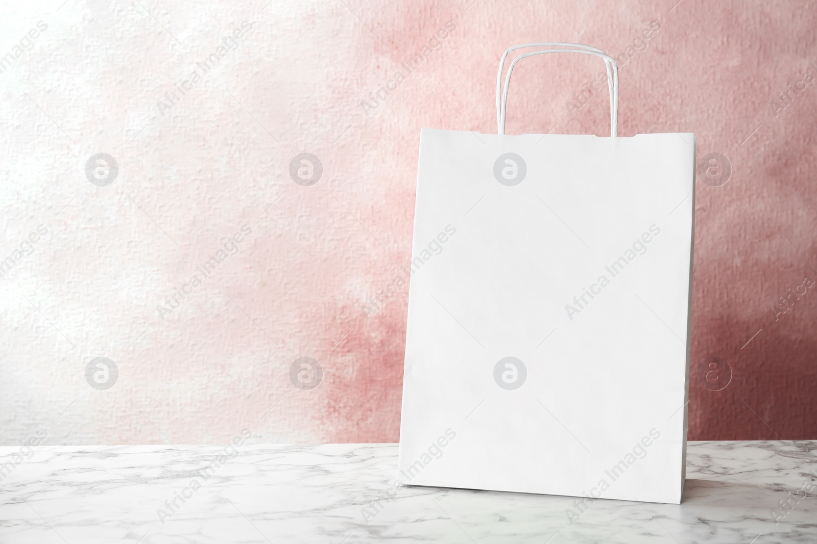 Photo of Mockup of paper shopping bag on table against color background