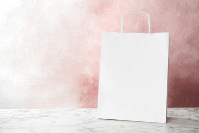 Photo of Mockup of paper shopping bag on table against color background