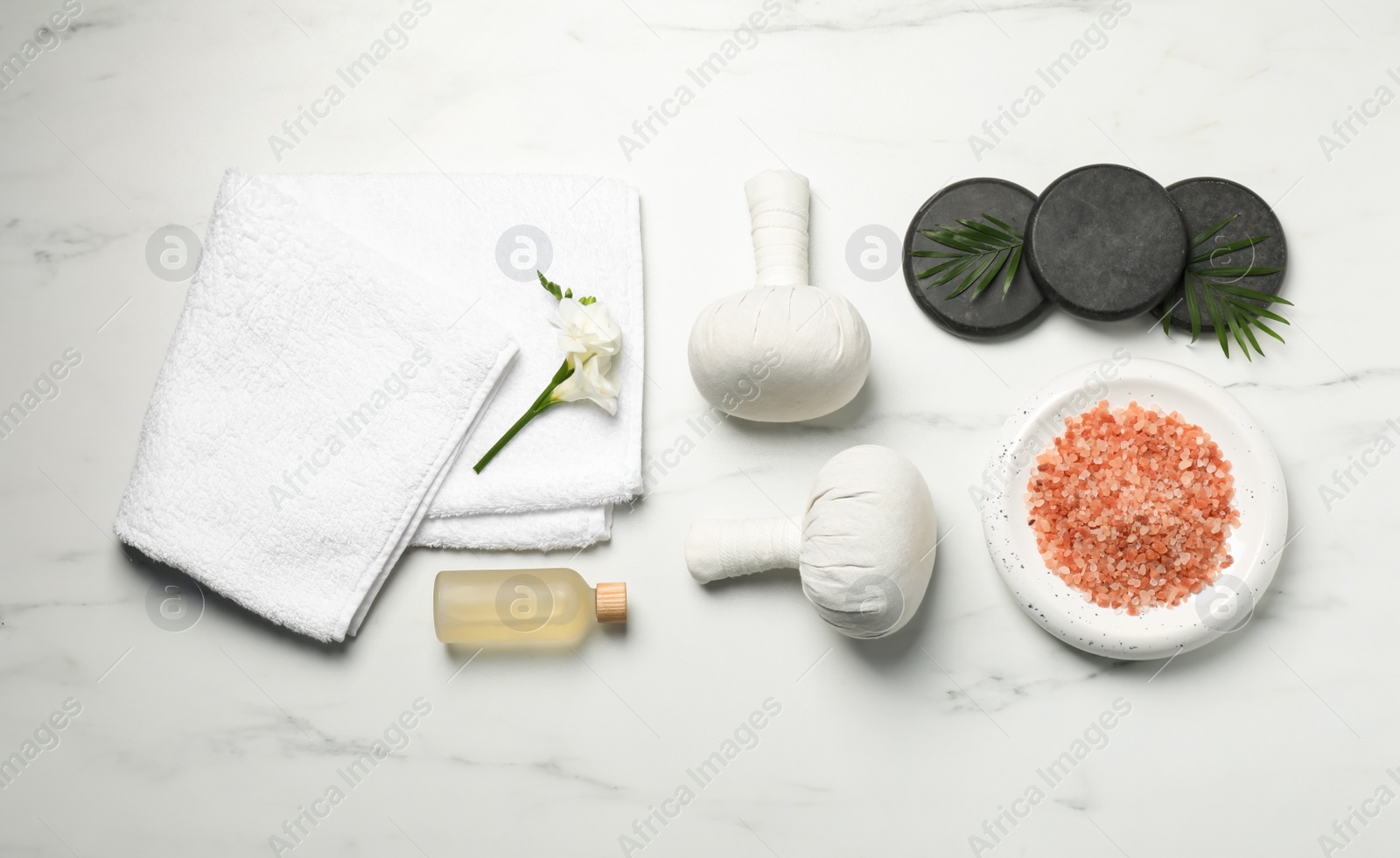 Photo of Spa bags, pink salt and essential oil on white marble table, flat lay