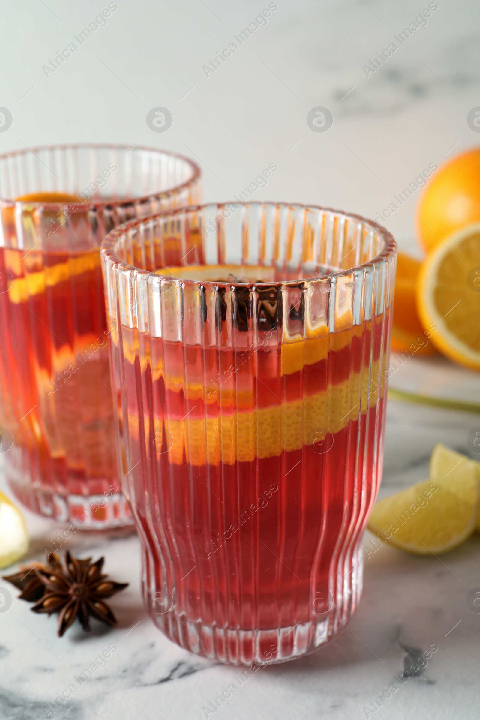 Photo of Aromatic punch drink and ingredients on white marble table