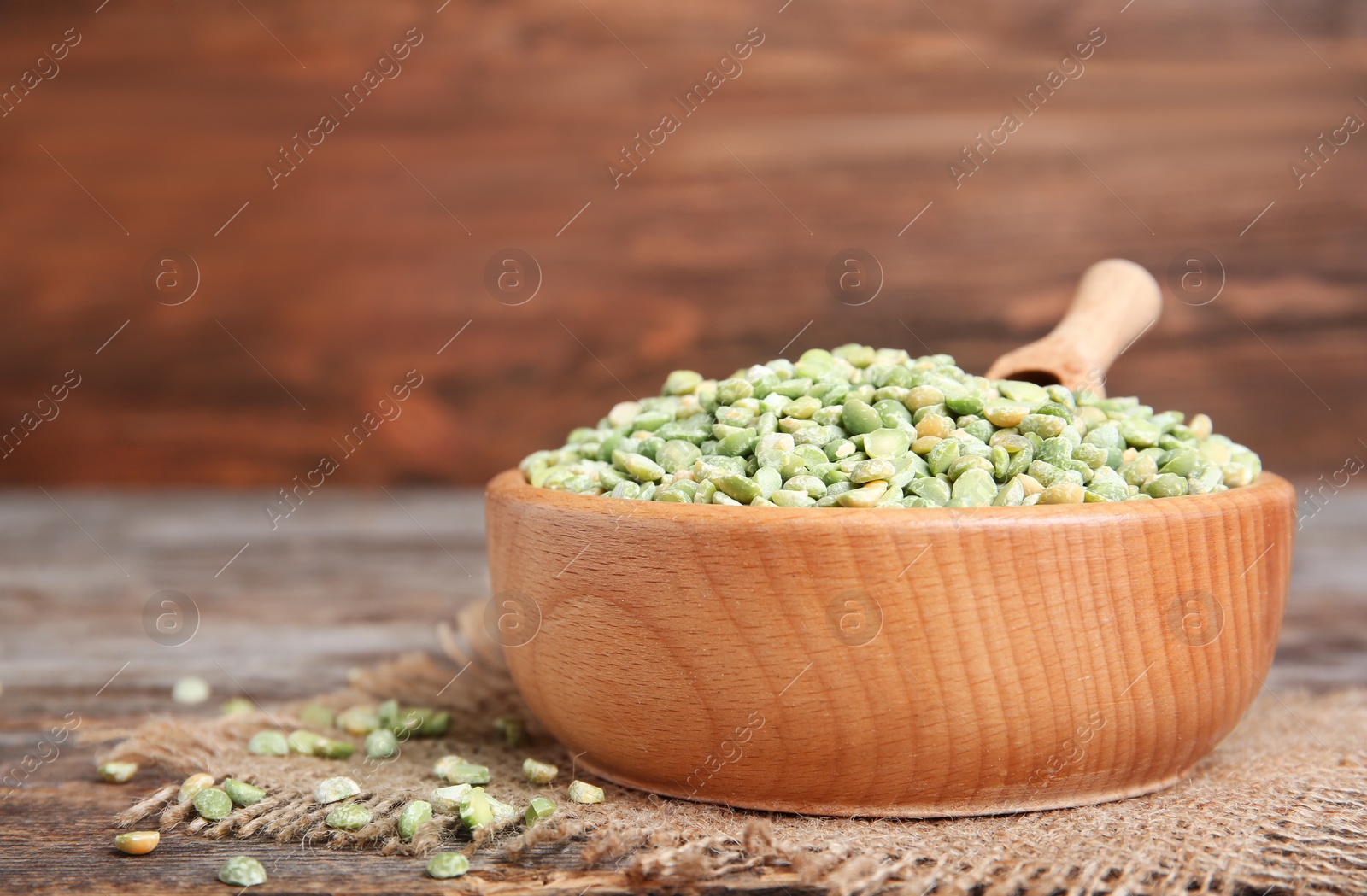 Photo of Wooden bowl with dried peas on table