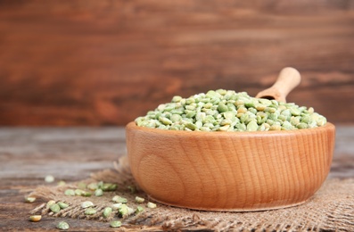 Photo of Wooden bowl with dried peas on table