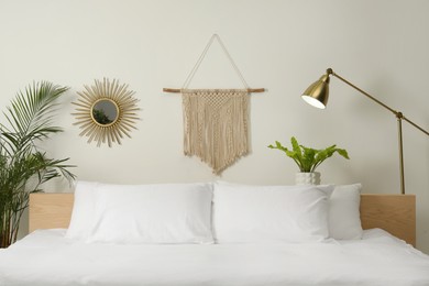 Photo of Stylish macrame hanging on white wall in bedroom