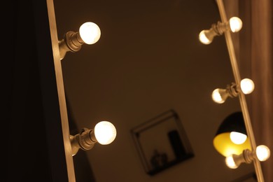 Photo of Beautiful mirror with light bulbs in makeup room, closeup