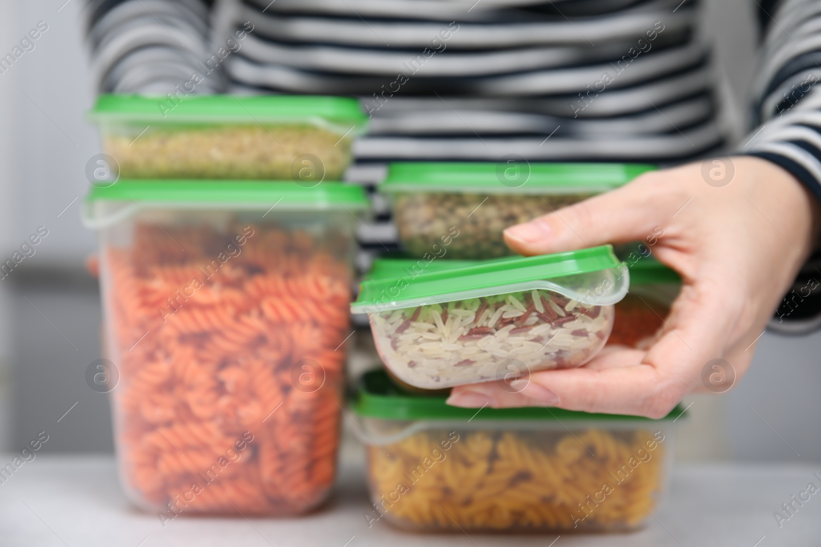 Photo of Woman with plastic containers filled of food products at light table indoors, selective focus