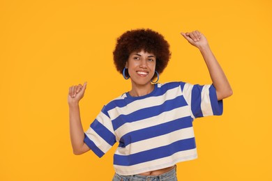 Photo of Happy young woman dancing on orange background