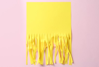 Photo of Half shredded sheet of yellow paper on pink background, top view