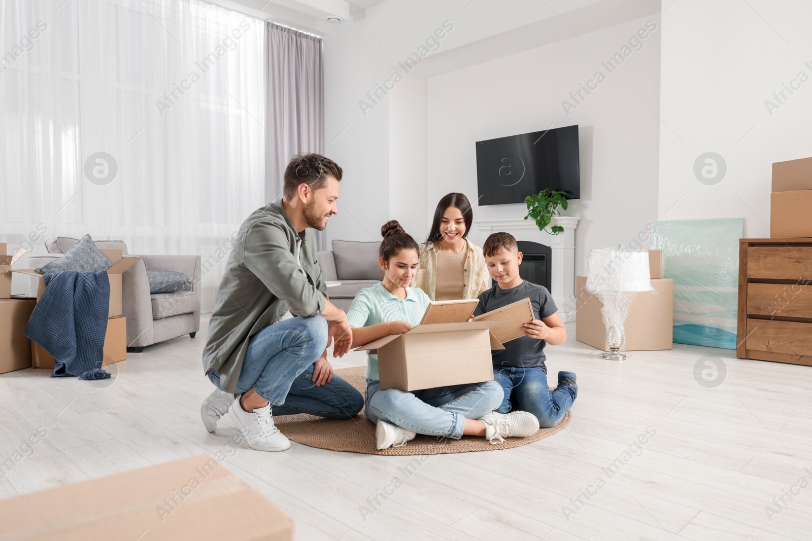 Photo of Happy family settling into new house and unpacking boxes on floor. Moving day