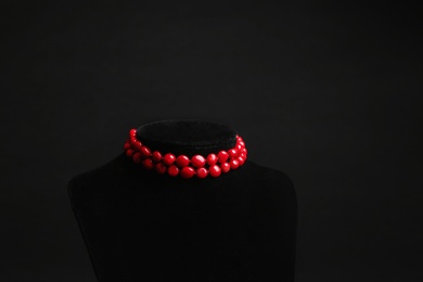 Stylish jewelry on stand against black background, space for text