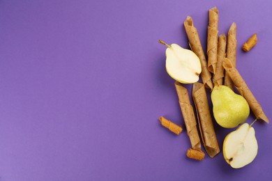 Photo of Delicious fruit leather rolls and pears on purple background, flat lay. Space for text