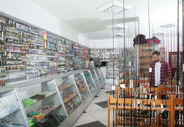 Customer choosing fishing equipment in sports shop