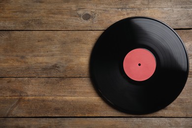 Photo of Vintage vinyl record on wooden background, top view. Space for text